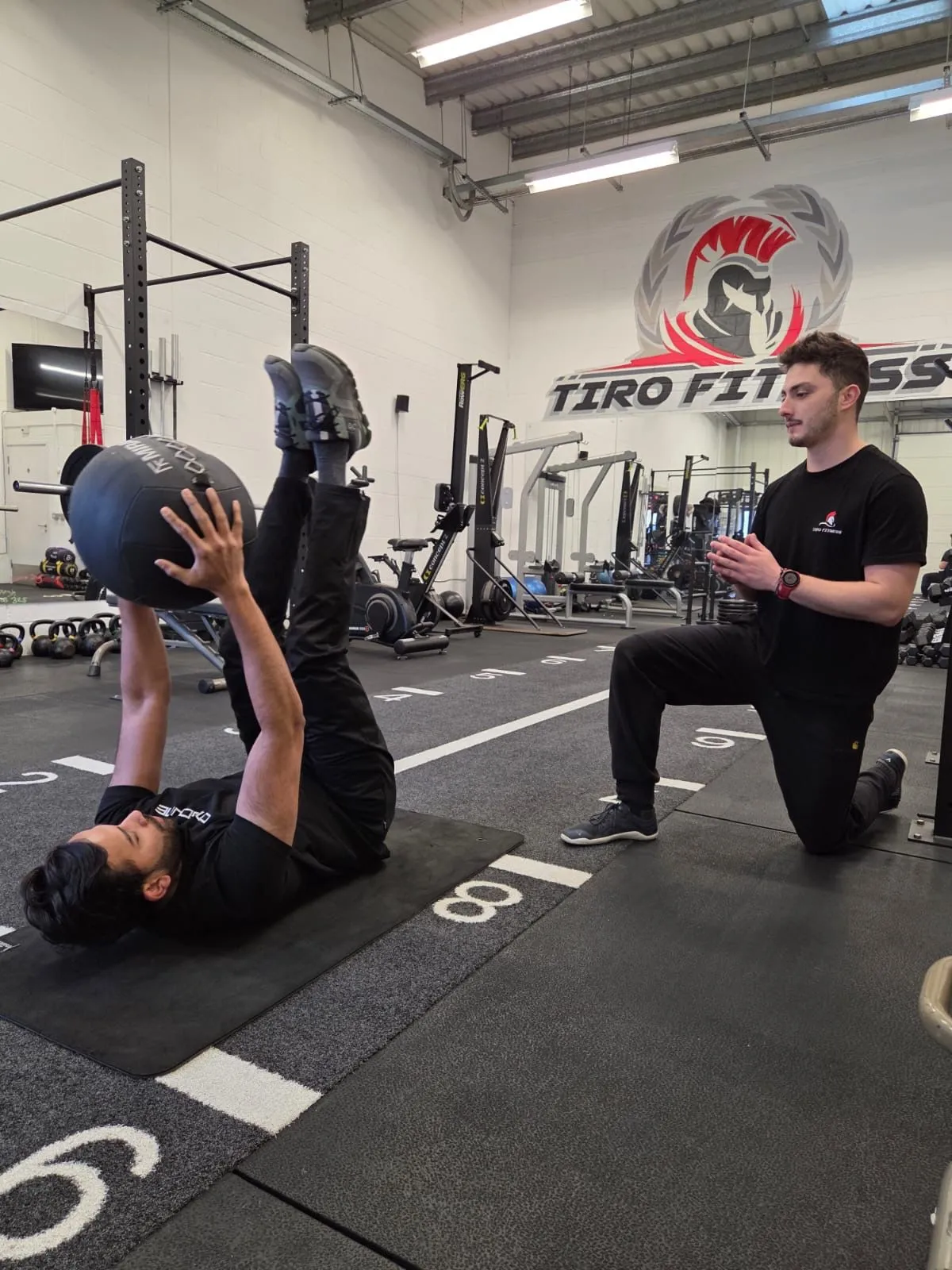 Personal trainer coaching a client through a medicine ball exercise