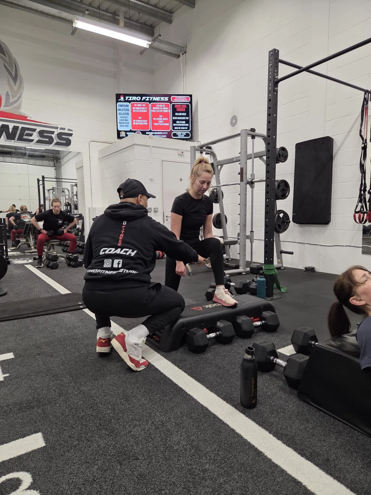 Coach working with a client during a group training session at Tiro Fitness